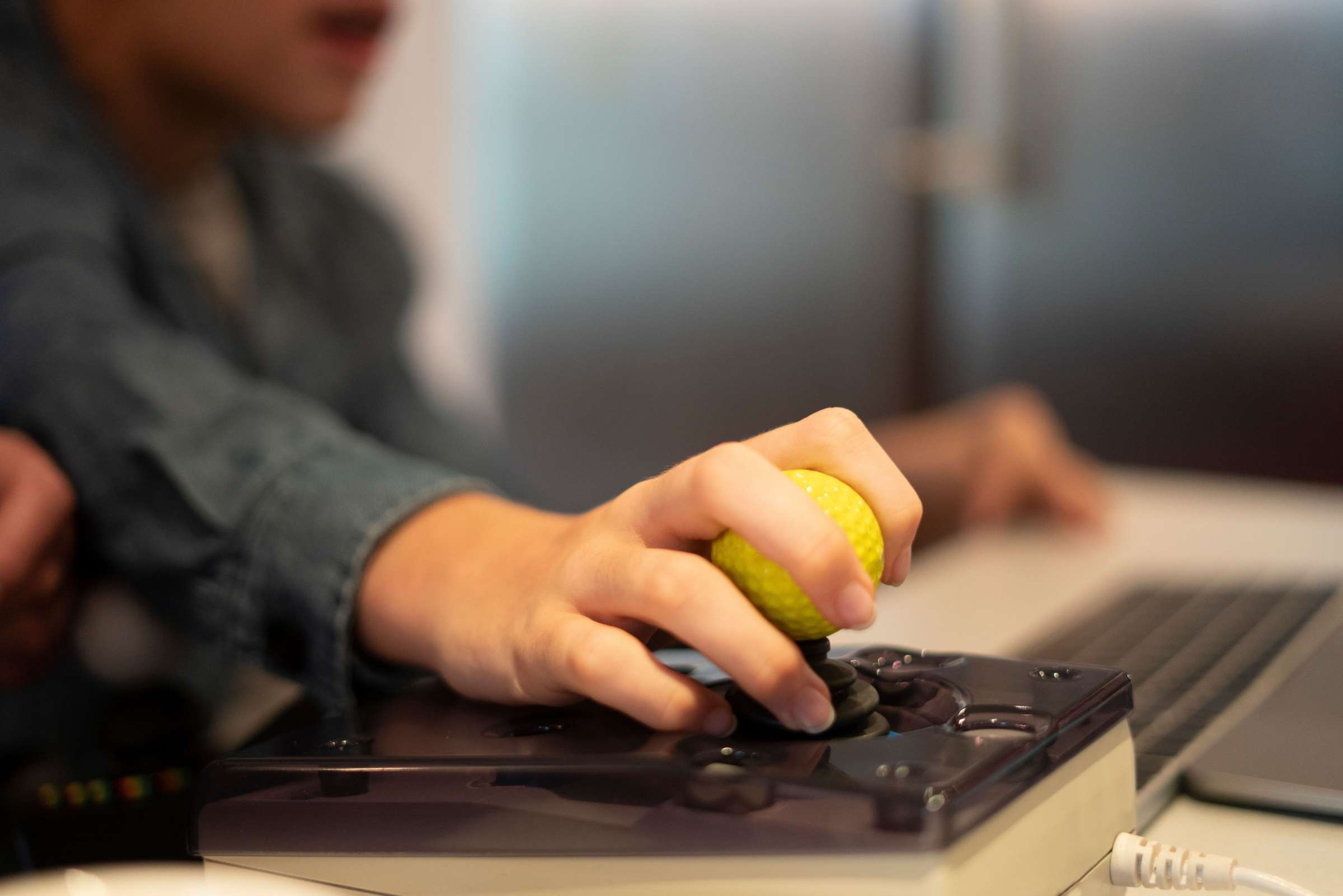 A person using an accessible joystick to navigate on their computer.